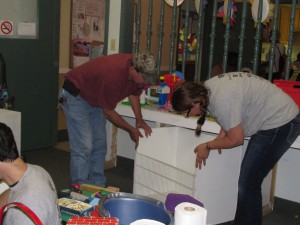 Avery Dennison’s Mike Webster, left, and Susan Rhodes replace a bin in the playroom after  empting it of a jumble of toys and thoroughly washing it.